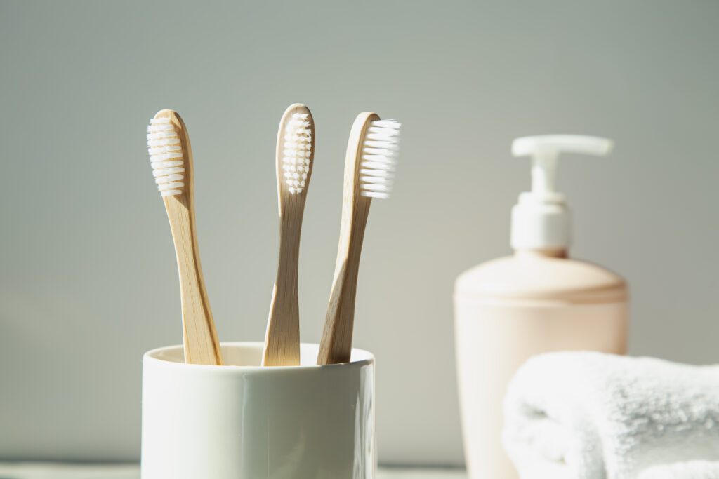 Natural bamboo toothbrushes, soap container and towels on a ligh